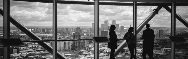 An image showing an office relocation in progress with people looking out large windows over the city