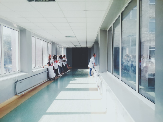 an image of a hallway in a hospital, which is light because of large windows and a light-colours suspended ceiling